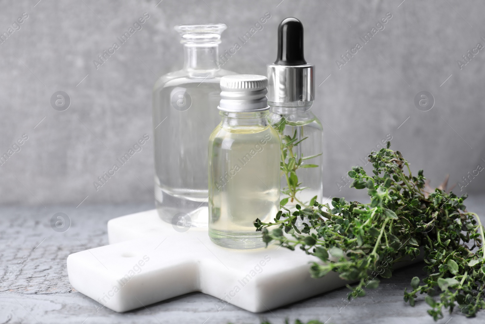 Photo of Thyme essential oil on light blue wooden table