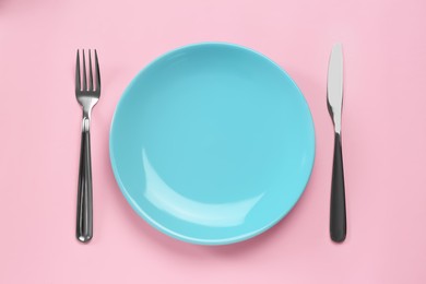 Photo of Clean plate and shiny silver cutlery on pink background, flat lay