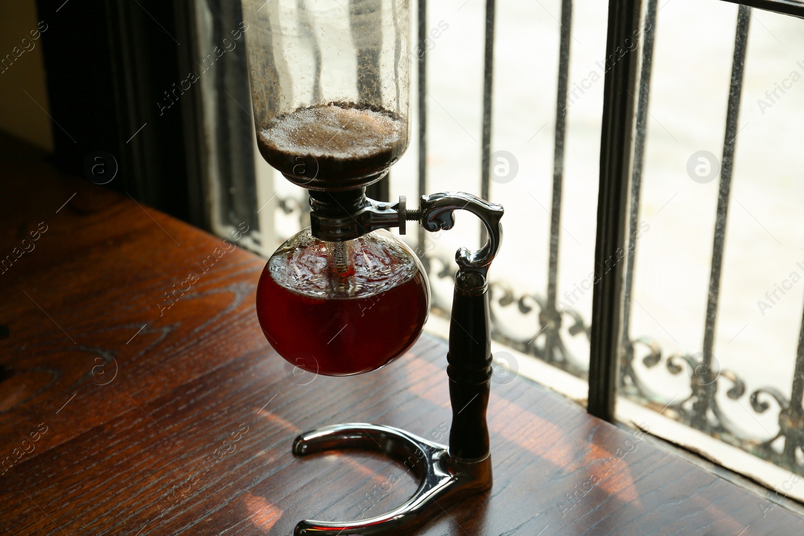 Photo of Vacuum coffee maker on wooden table in cafe