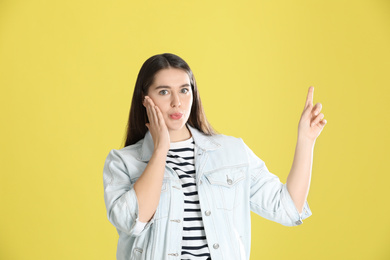 Portrait of young emotional young woman on yellow background