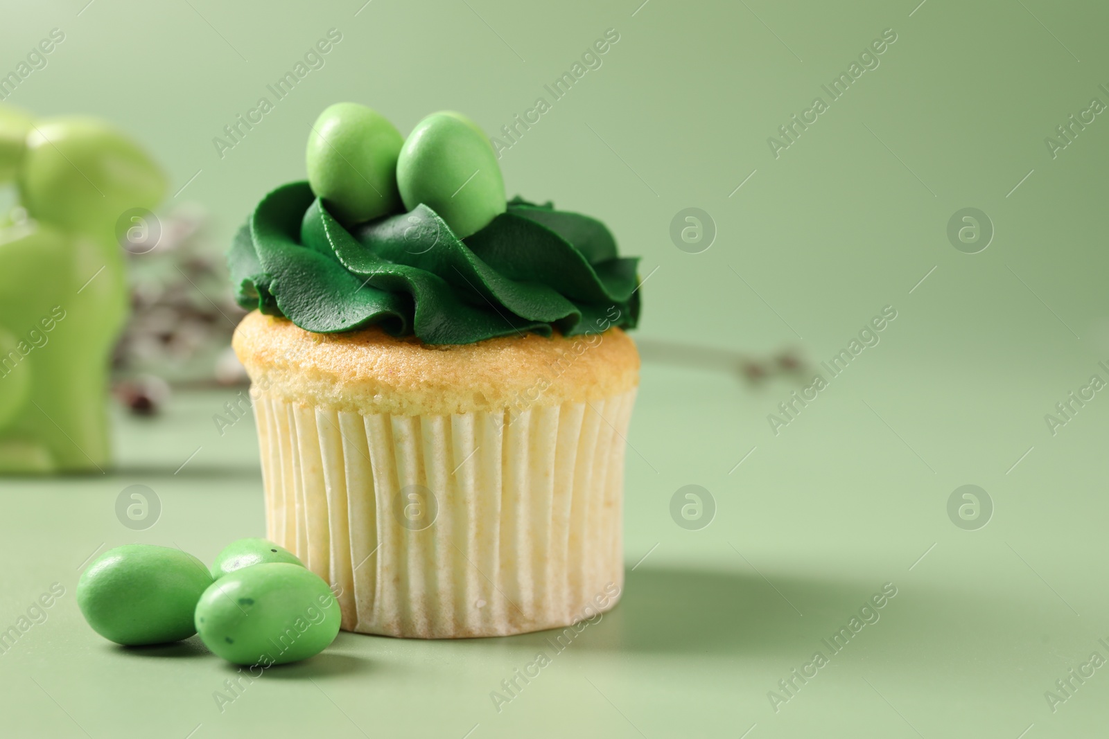 Photo of Tasty cupcake with Easter decor on green background, closeup. Space for text