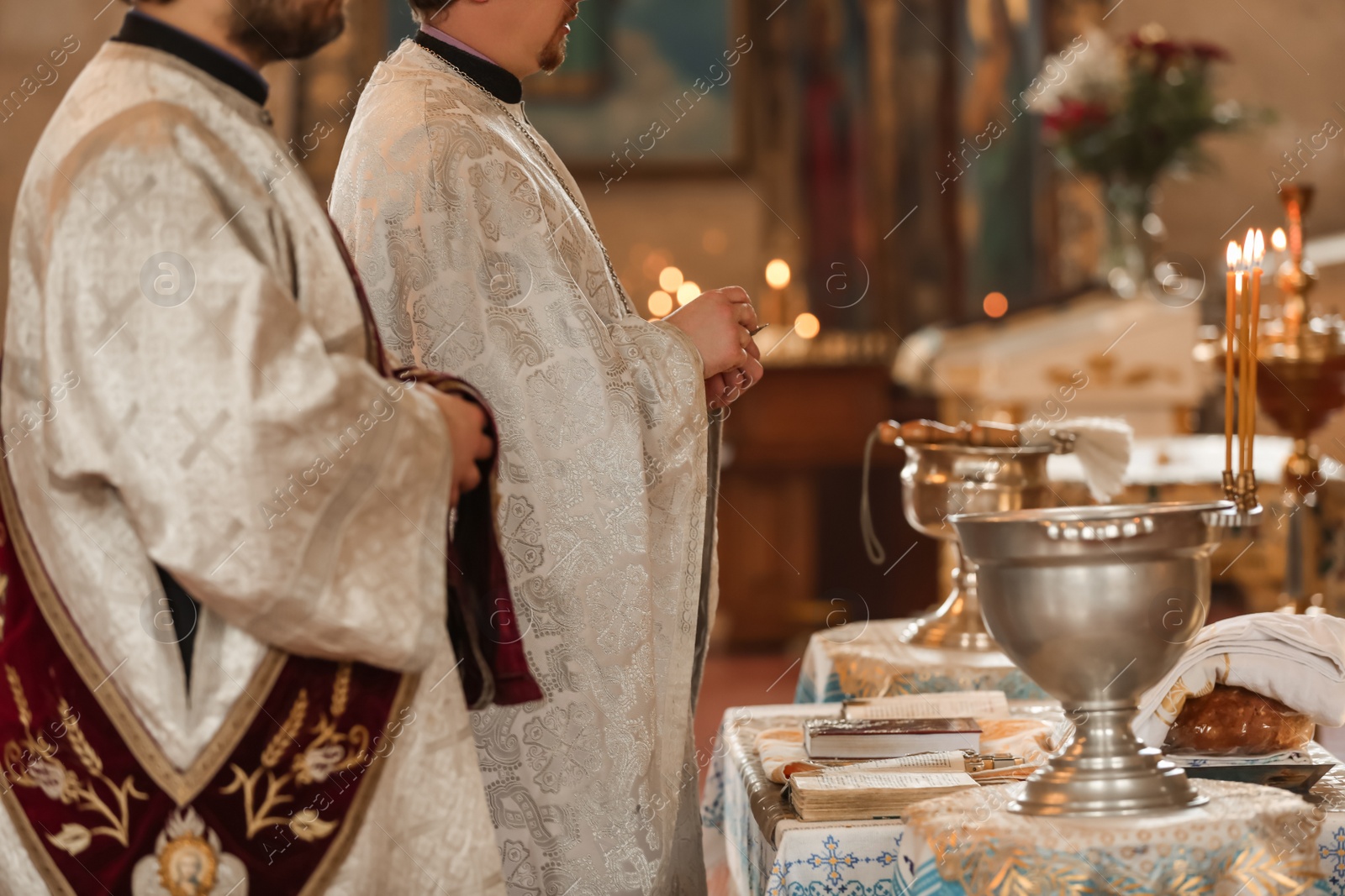 Photo of MYKOLAIV, UKRAINE - FEBRUARY 27, 2021: Deacon and priest conducting baptism ceremony in Kasperovskaya icon of Mother of God cathedral, closeup