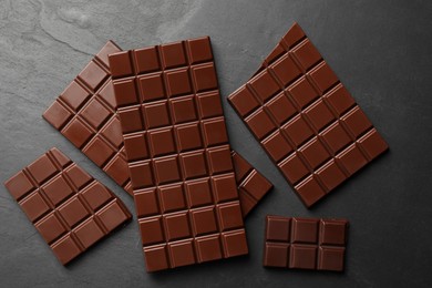 Pieces of tasty chocolate bars on grey table, flat lay