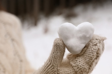 Photo of Woman holding heart made of snow, closeup view