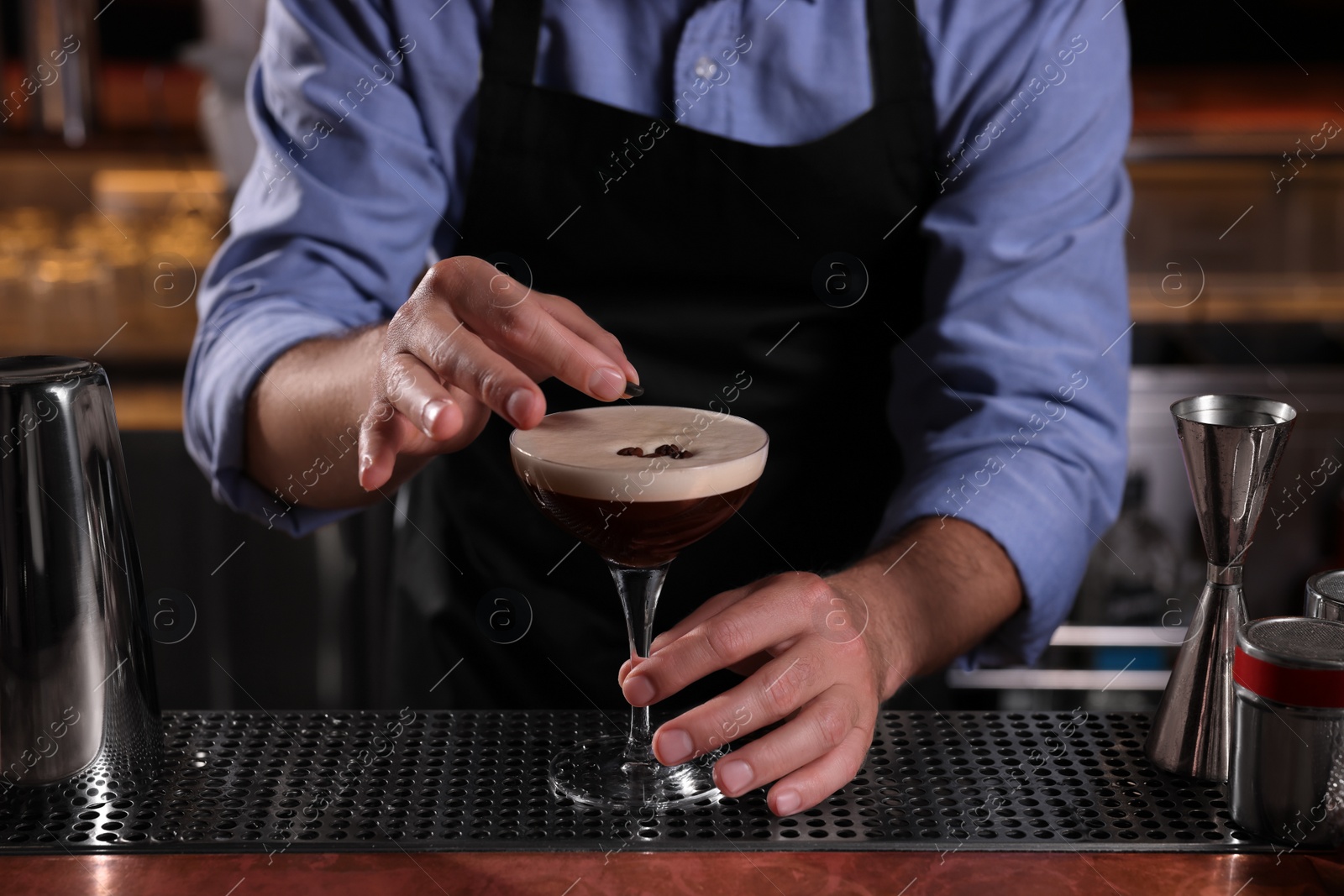 Photo of Bartender preparing Espresso Martini in bar, closeup. Alcohol cocktail