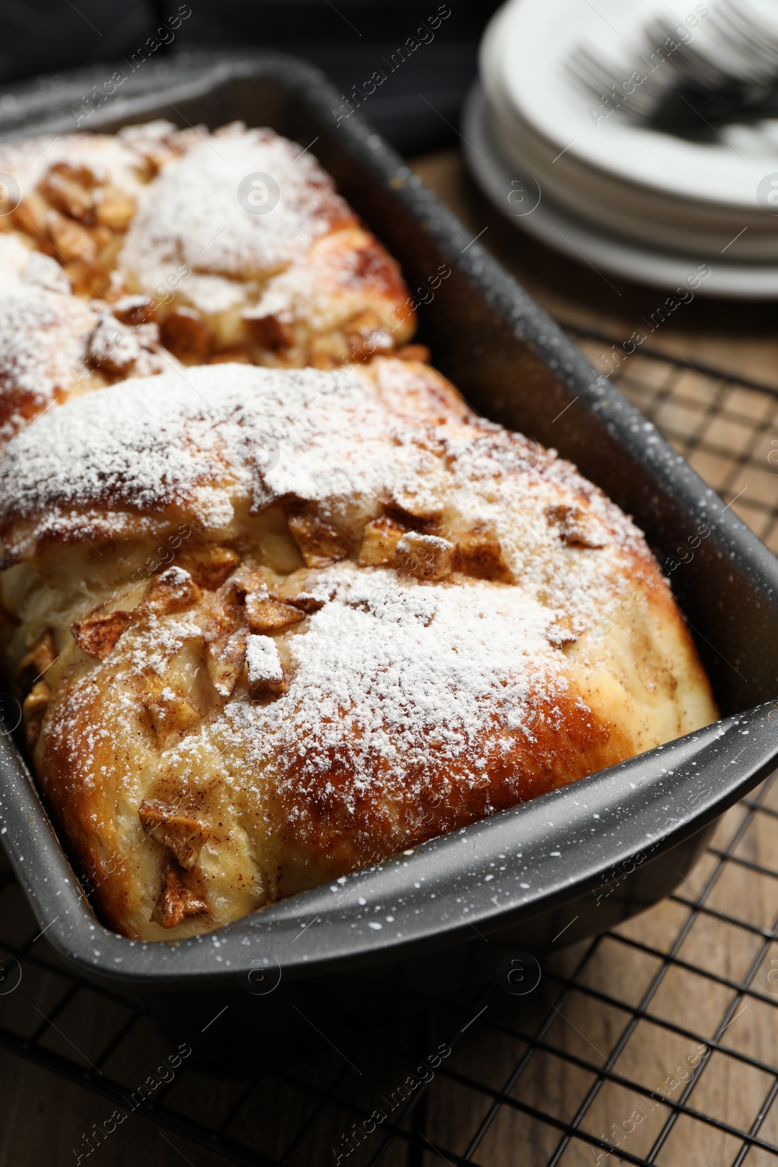 Photo of Delicious yeast dough cake in baking pan on wooden table, closeup