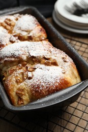 Photo of Delicious yeast dough cake in baking pan on wooden table, closeup