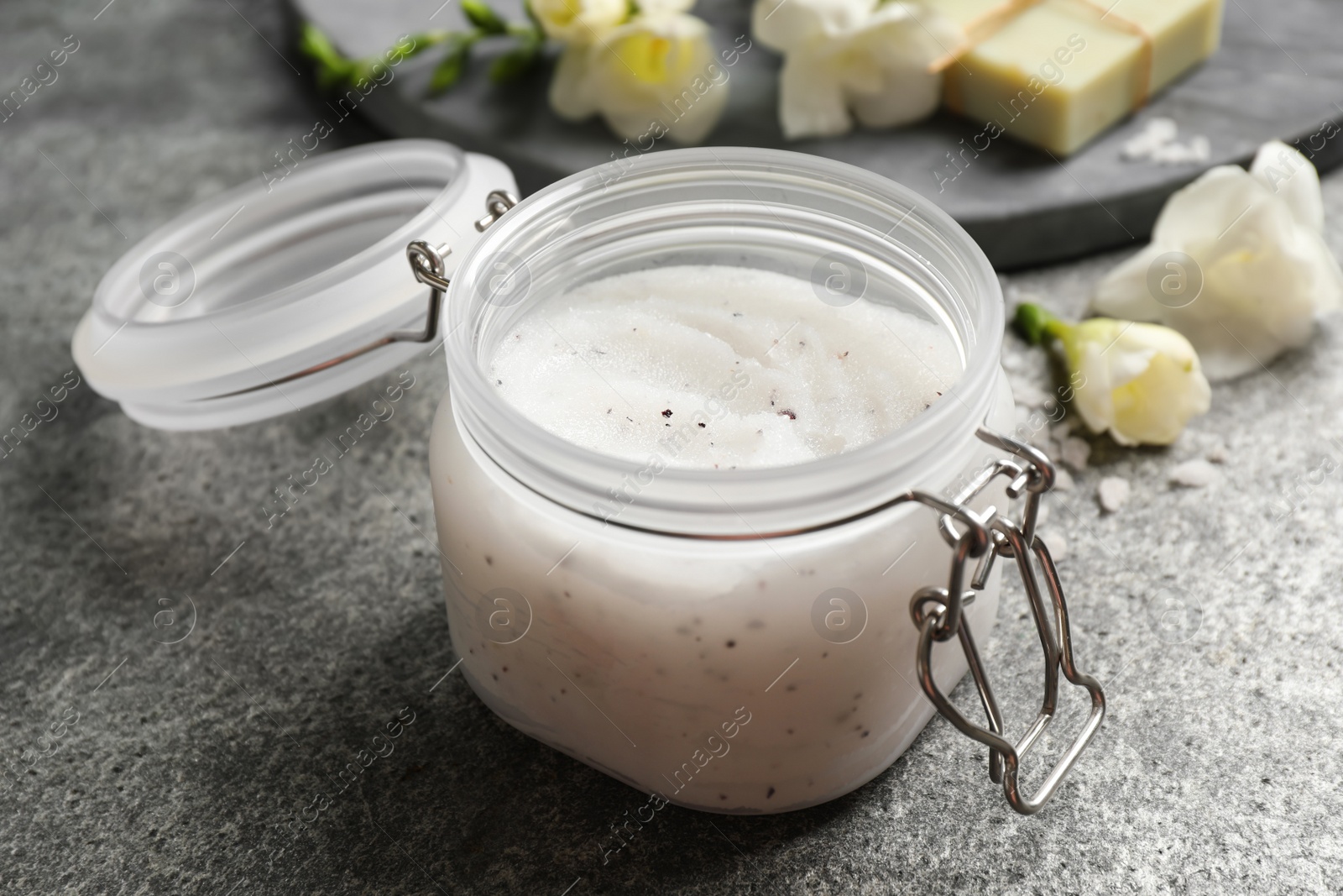 Photo of Body scrub in glass jar on grey table, closeup