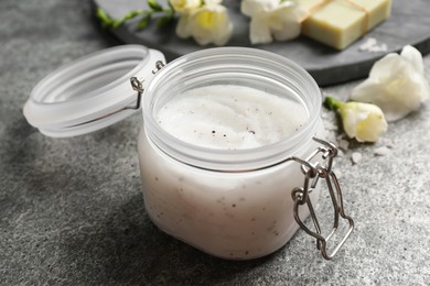 Body scrub in glass jar on grey table, closeup