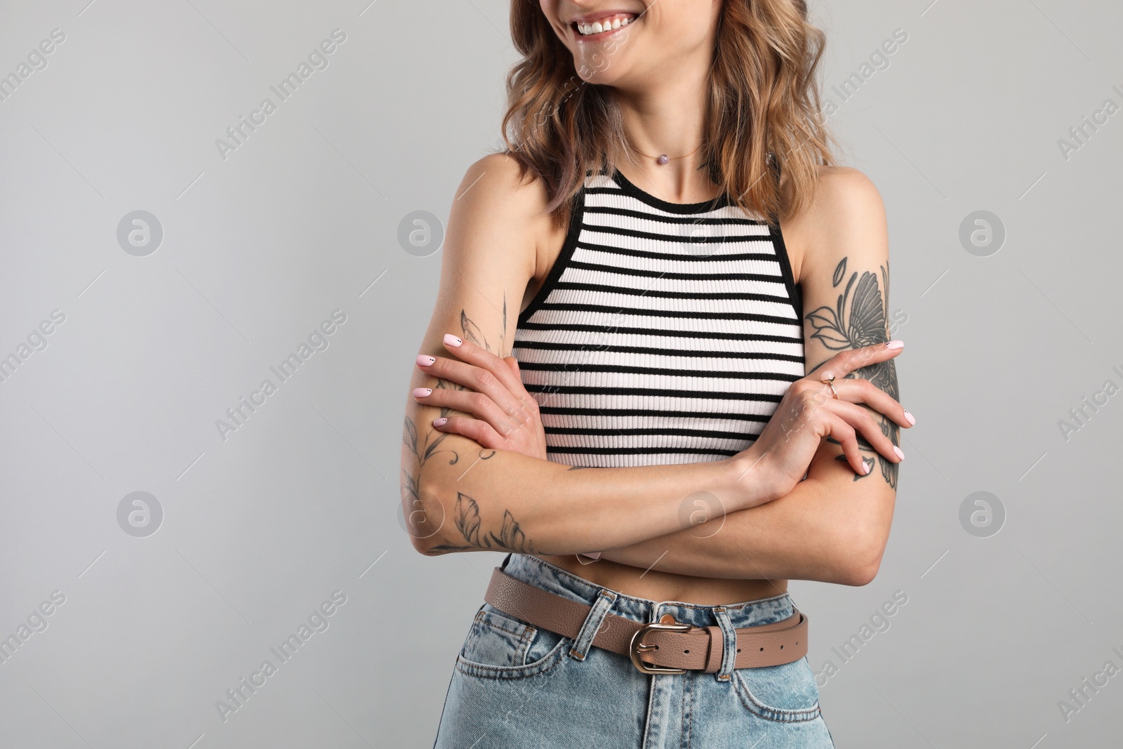 Photo of Beautiful woman with tattoos on body against grey background, closeup