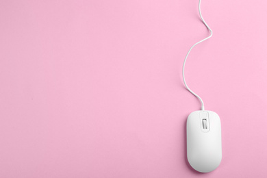 Photo of Modern wired optical mouse on pink background, top view. Space for text