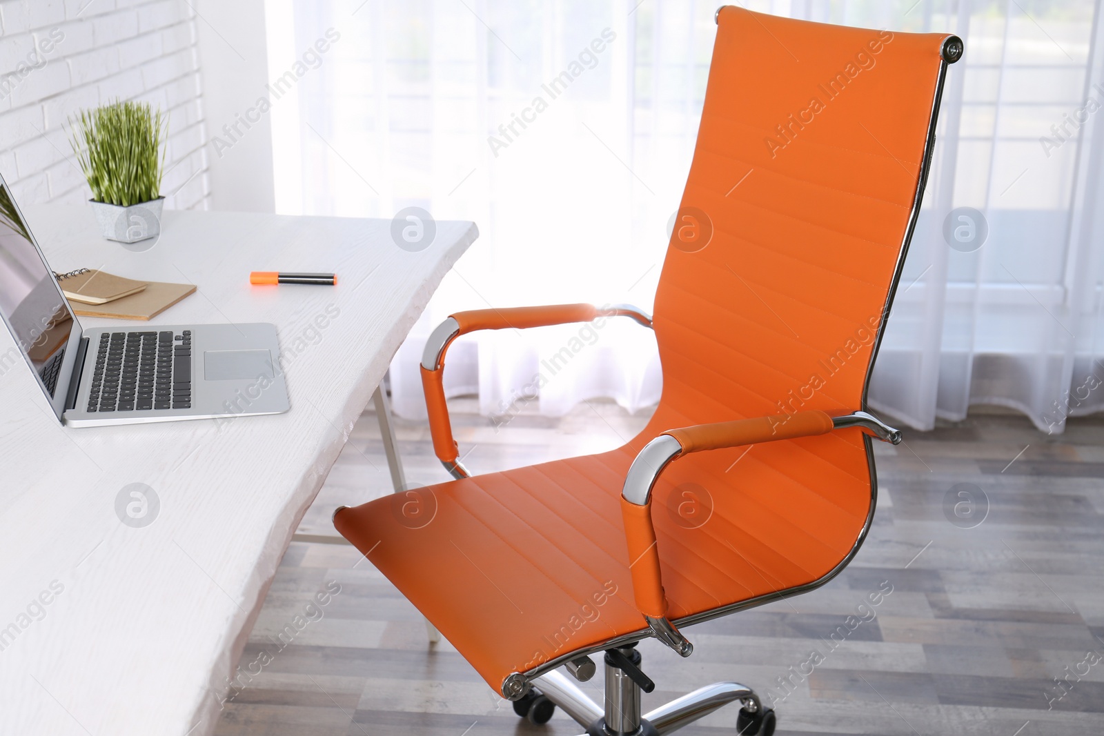 Photo of Comfortable workplace with office chair and wooden table