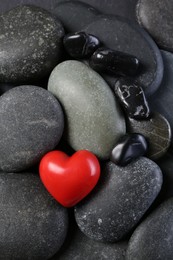 Photo of Red decorative heart on pebble stones, top view