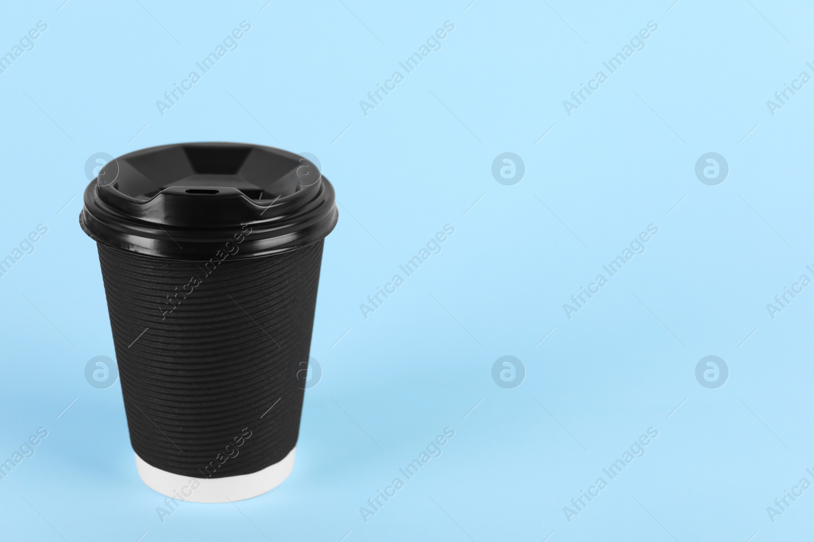 Photo of Black paper cup with plastic lid on light blue background, space for text. Coffee to go