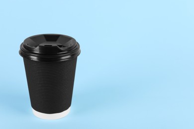 Photo of Black paper cup with plastic lid on light blue background, space for text. Coffee to go