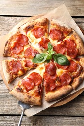 Photo of Tasty pepperoni pizza with basil on wooden table, top view