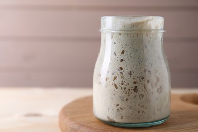 Sourdough starter in glass jar on table, closeup. Space for text