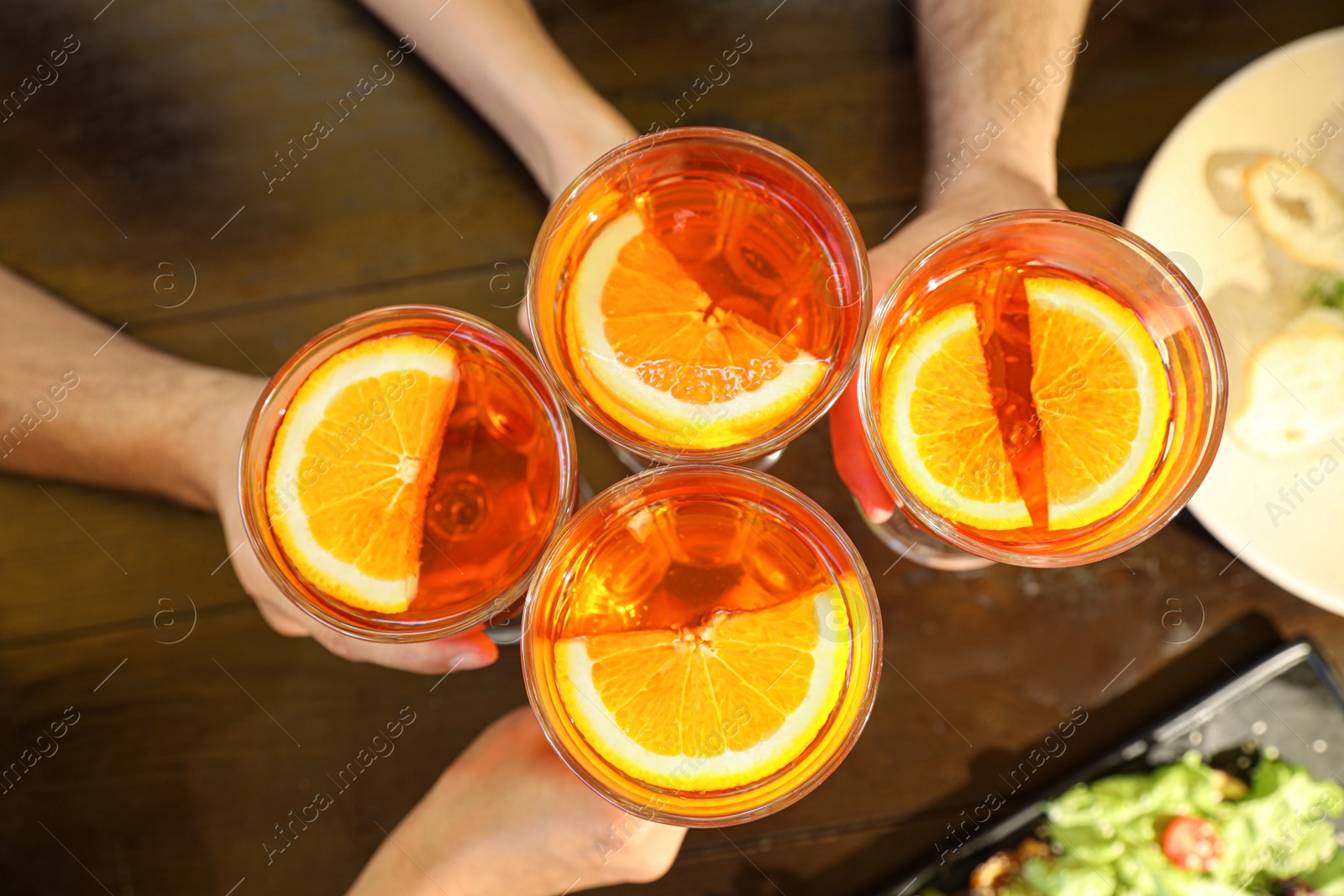Photo of Friends with Aperol spritz cocktails together at wooden table, top view