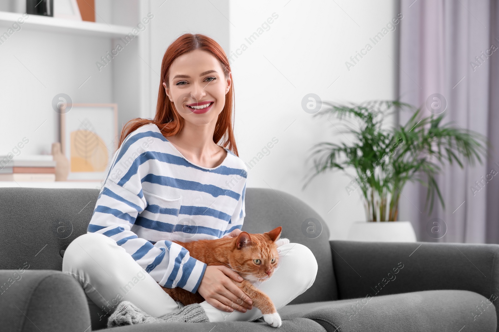 Photo of Happy woman with her cute cat on sofa at home