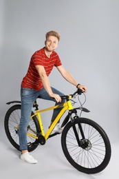 Photo of Handsome young man riding bicycle on grey background