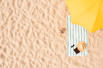 Image of Beach umbrella near towel and other vacationist's stuff on sand, aerial view. Space for text