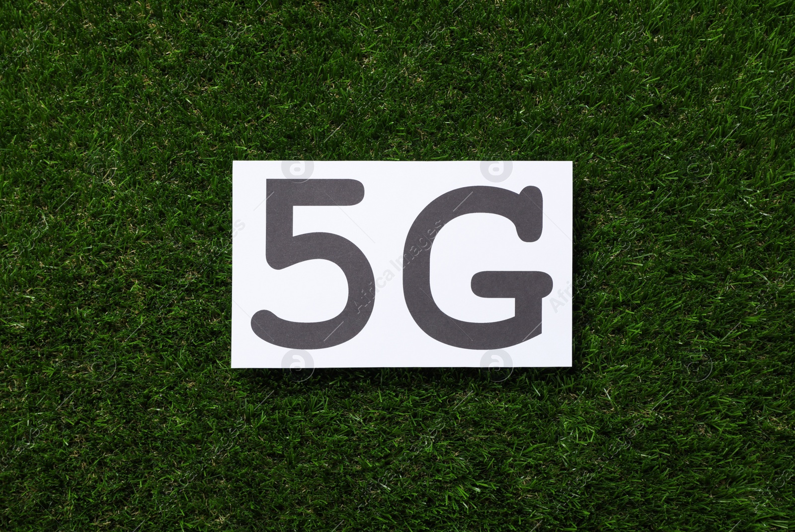 Photo of 5G technology, Internet concept. Card on green grass, top view