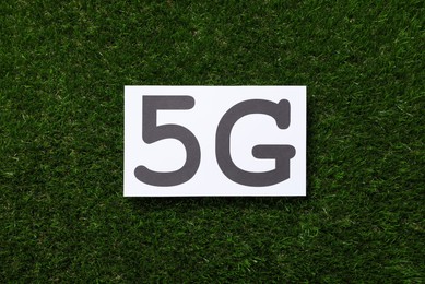 Photo of 5G technology, Internet concept. Card on green grass, top view