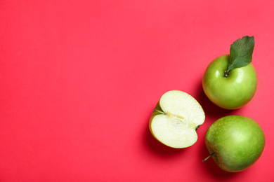 Juicy green apples on red background, flat lay. Space for text