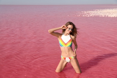 Beautiful woman posing in pink lake on sunny day