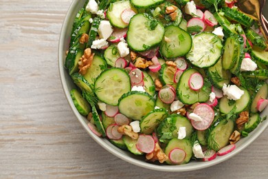 Bowl of delicious cucumber salad on white wooden table, top view