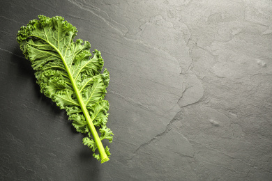 Photo of Fresh kale leaf on black table, top view. Space for text