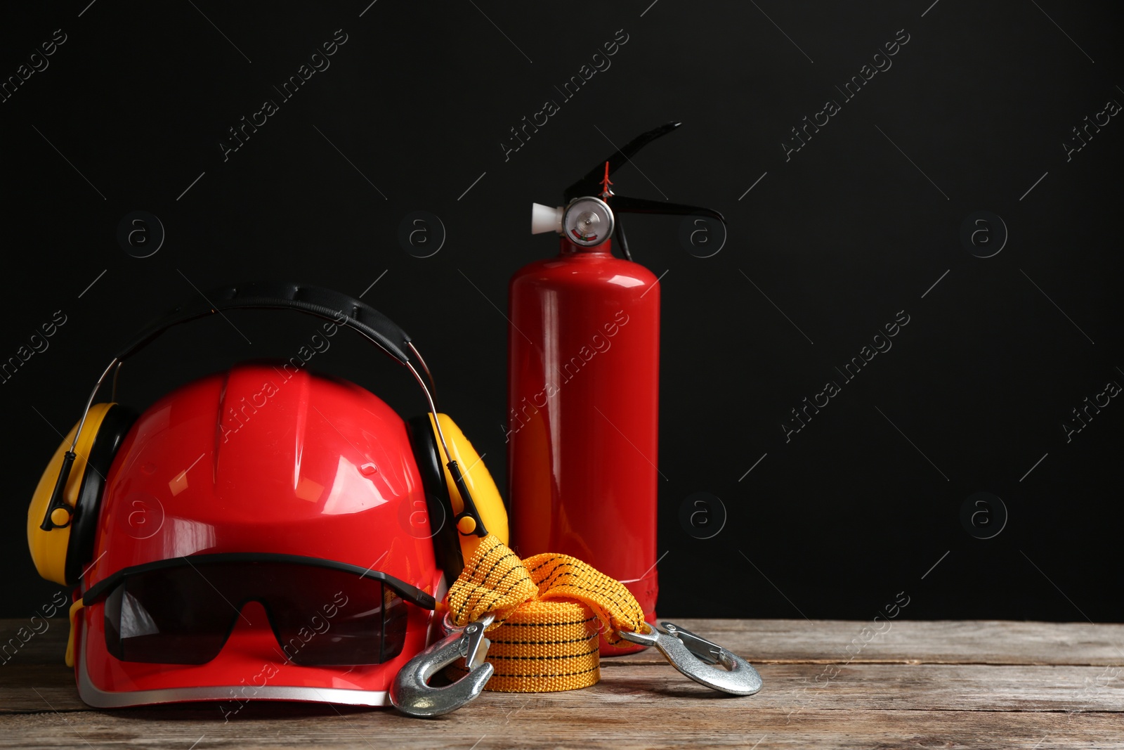 Photo of Different safety equipment on wooden table against black background. Space for text