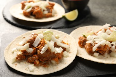 Photo of Delicious tacos with vegetables, meat and lime on grey table, closeup