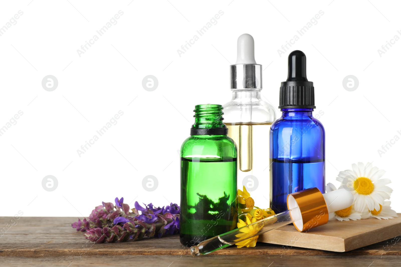 Photo of Bottles of different essential oils and wildflowers on wooden table, white background