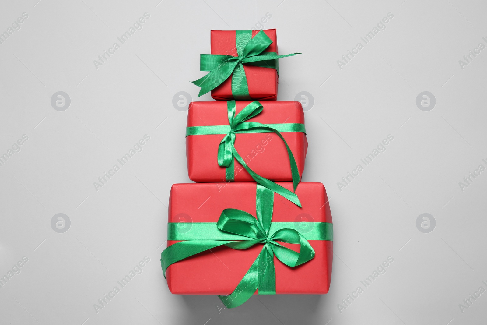 Photo of Christmas tree shape of gift boxes on light grey background, flat lay