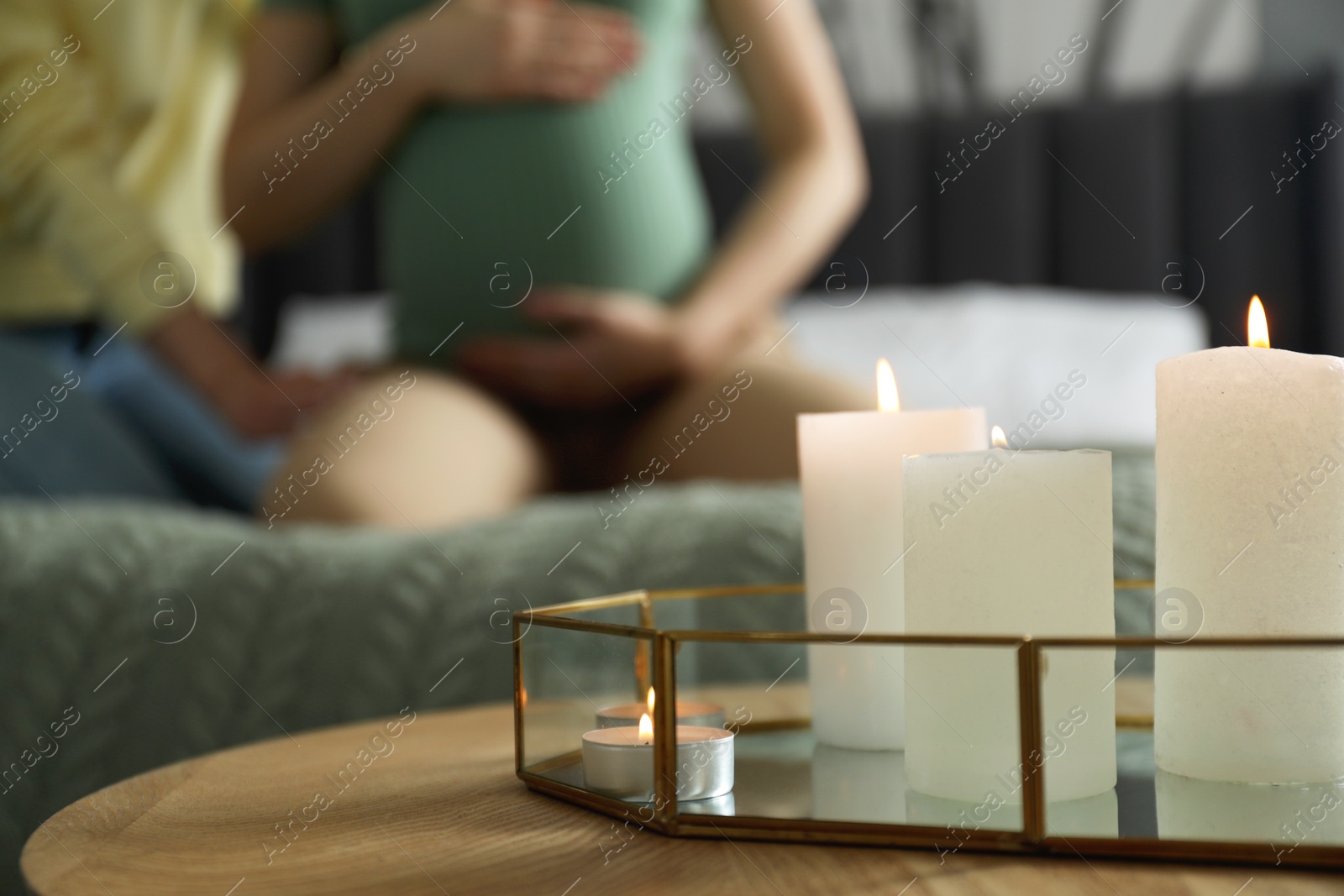 Photo of Doula working with pregnant woman indoors, focus on burning candles. Preparation for child birth