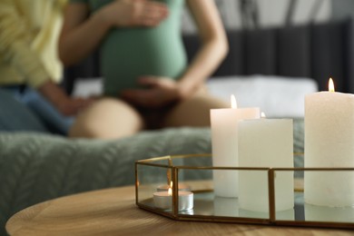Photo of Doula working with pregnant woman indoors, focus on burning candles. Preparation for child birth