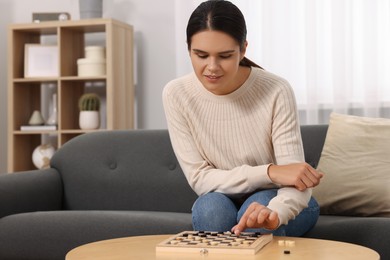 Woman playing checkers on sofa at home