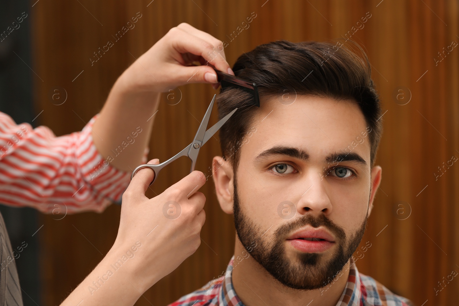 Photo of Barber making stylish haircut with professional scissors in beauty salon