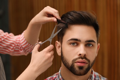 Barber making stylish haircut with professional scissors in beauty salon