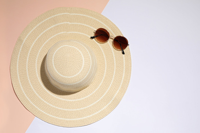 Stylish hat and sunglasses on color background, top view. Beach objects