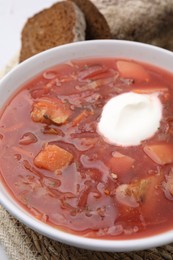 Photo of Tasty borscht with sour cream on table, closeup