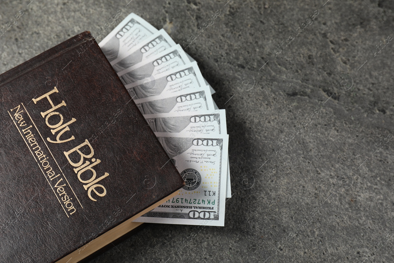 Photo of Holy Bible and money on grey table, top view. Space for text