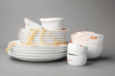 Photo of Set of dirty dishes with spaghetti leftovers on grey background