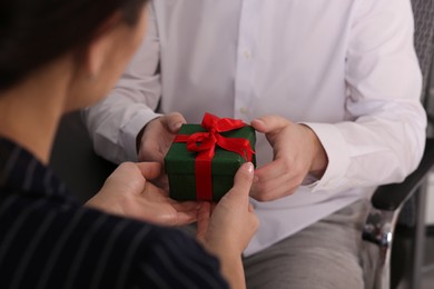 Photo of Woman presenting gift to her colleague, closeup