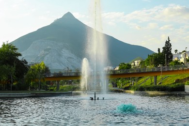 Photo of Picturesque view of park with fountain near mountains