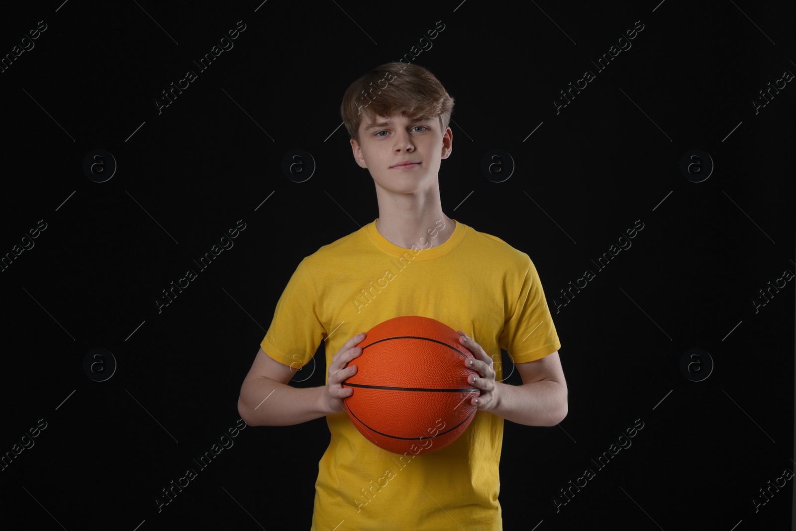 Photo of Teenage boy with basketball ball on black background