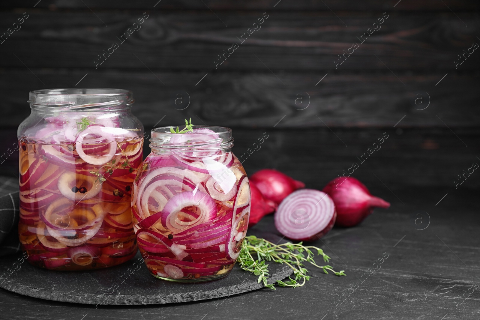 Photo of Jars of pickled onions on grey table, space for text