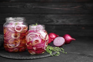Photo of Jars of pickled onions on grey table, space for text