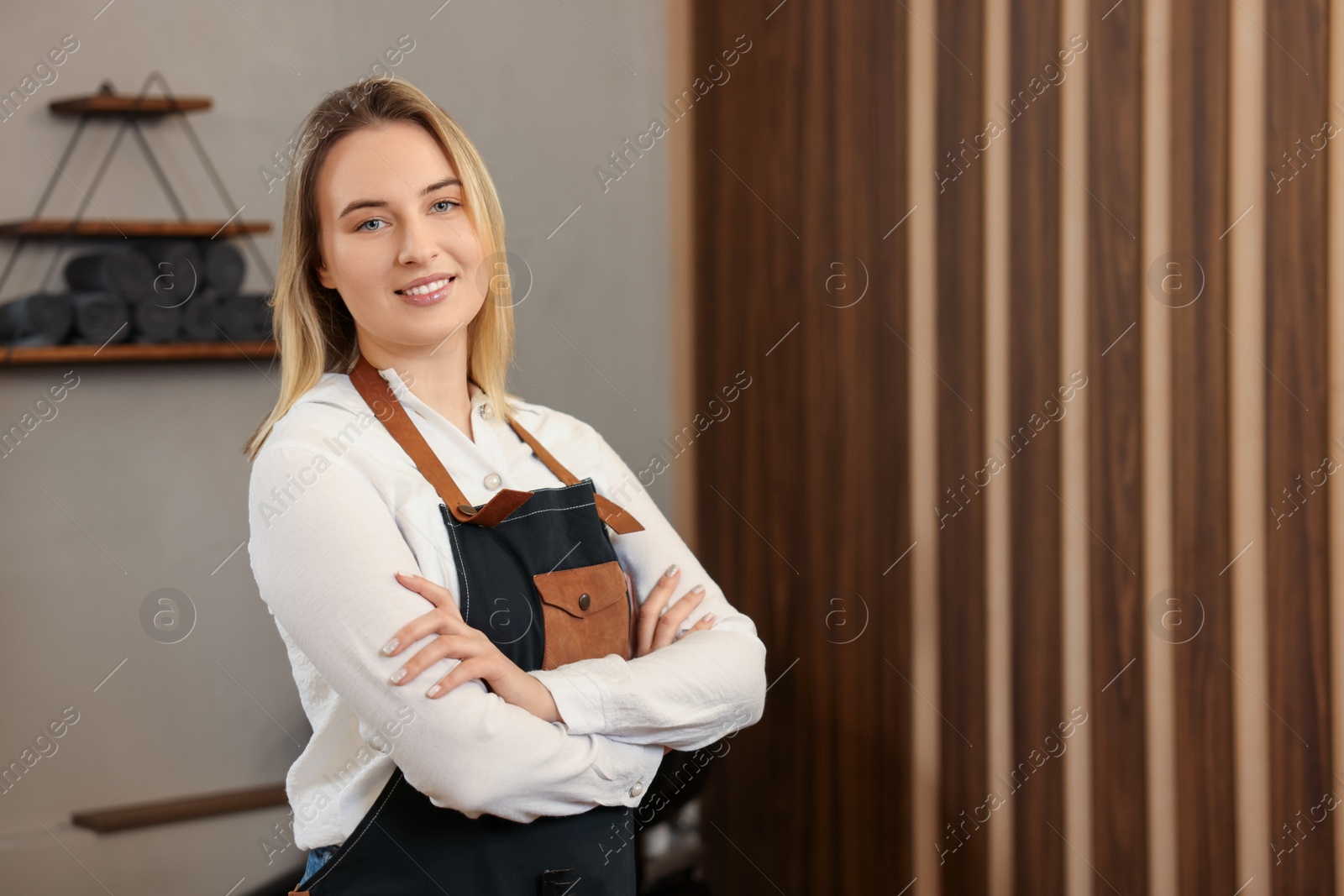 Photo of Portrait of professional hairdresser wearing apron in beauty salon, space for text